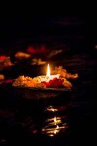 floating candle in water surrounded by flowers at night